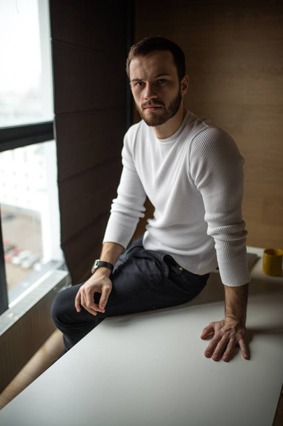 Bearded young businessman in white pullover working at computer. - Foto, afbeelding
