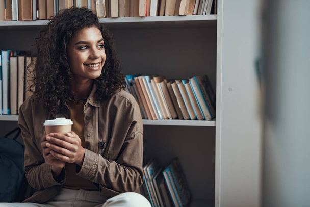 Waist up of pretty curly lady smiling and enjoying her coffee - Fotoğraf, Görsel