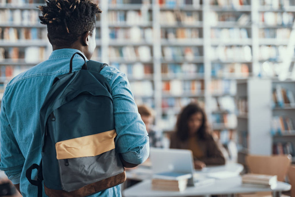 Afro-American student coming to the library and carrying his backpack - 写真・画像