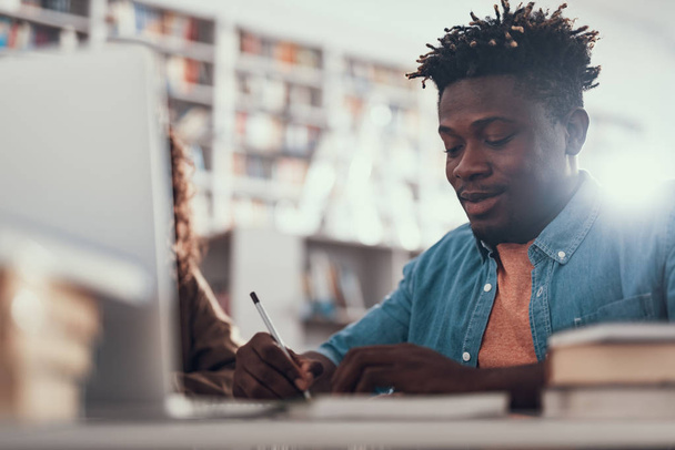 Calm Afro-American young man making notes and smiling - Photo, image