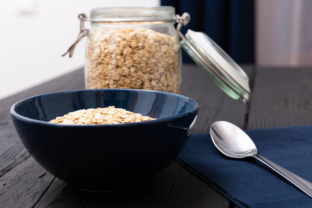 Rolled oats, healthy breakfast cereal oat flakes in bowl on dark wooden table with texture - Foto, Imagem
