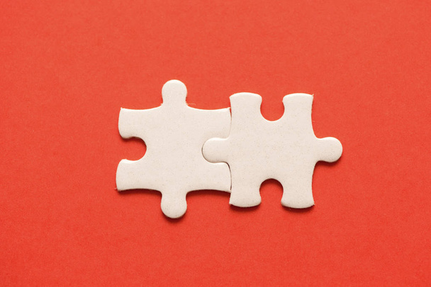 Two white details of puzzle on red background. - Photo, Image
