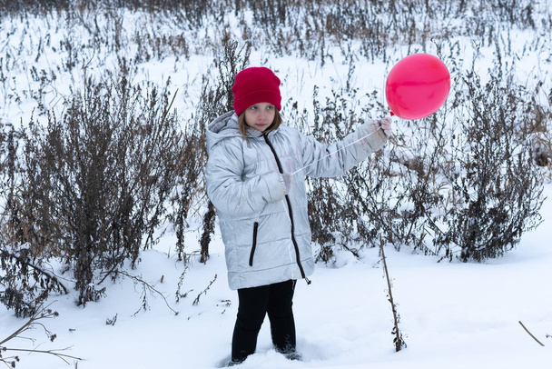 young girl posing outside in winter, standing with a red ball - Fotó, kép