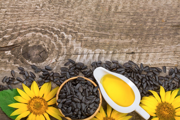 Olej słonecznikowy, nasion i kwiatów na podłoże drewniane z miejsca kopiowania tekstu. Widok z góry - Zdjęcie, obraz