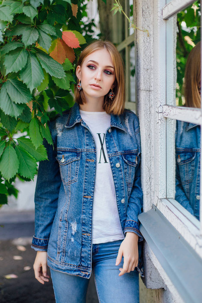 Fashion girl standing outdoors in denim oversized jacket and beautiful ear rings. - Fotoğraf, Görsel