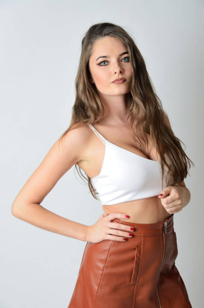 白いトップと茶色の革のスカートに良く造られたモデルです。若い魅力的な女性.  - 写真・画像