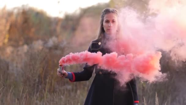 Fiatal nő séta a mező fölött borított őszi levelek, visel kabátot, gazdaságban füst szökőkút és létrehozása egy felhő a füst, ezen a környéken: ő 4k lassú Mo - Felvétel, videó