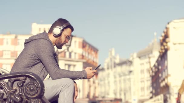 Νεαρός άνδρας με ακουστικά στον πάγκο - Πλάνα, βίντεο
