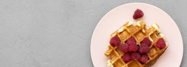 Traditional belgian waffle with raspberries on pink plate over concrete background, overhead view. Copy space. - Photo, Image