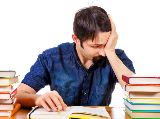 Уставший и проблемный студент за письменным столом на белом фоне - Фото, изображение