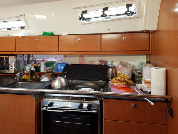 Yacht Bavaria cruiser. Maritimes kitchen. Kabuz. Frying fish in the galley of a sailing yacht. A healthy diet and a compelling lifestyle for active people at sea. Omega acids from animals - Photo, Image