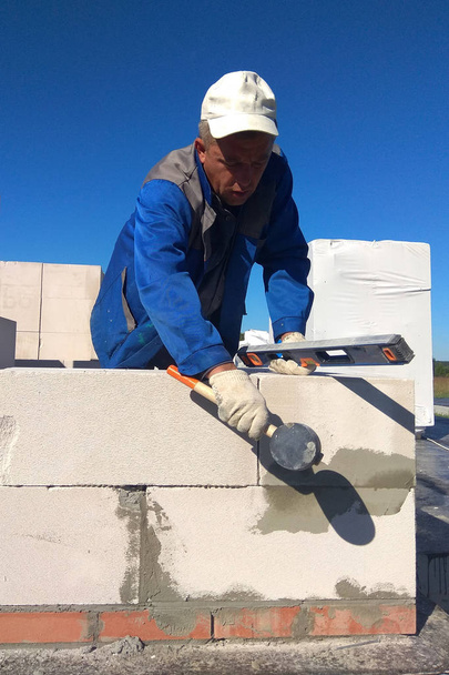 O trabalhador verifica a parede de blocos de gás por um nivelador 2018
 - Foto, Imagem