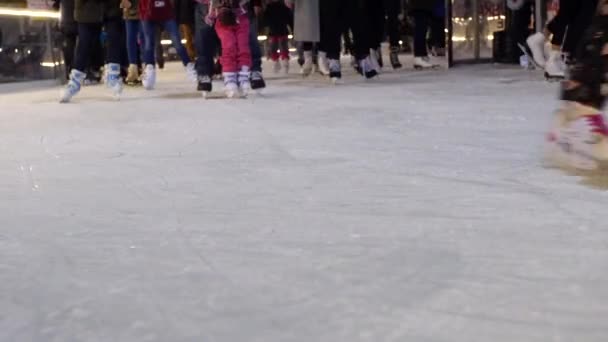 Nicht wiederzuerkennende Skaterfüße gleiten an Winterabenden über das Eis auf der Eisbahn. Menschen skaten auf der Eisbahn, Unterkörper-Ansicht von vorne. Eislaufen Familien, Kinder, Erwachsene und Jugendliche in der Nacht auf dem Weihnachtsmarkt. Gedrängtes Eis auf traditionellem Straßenfest - Filmmaterial, Video