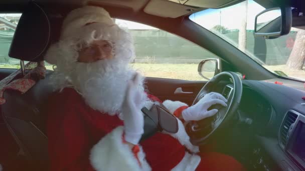 Nahaufnahme von glücklichen Weihnachtsmännern, die während der Autofahrt mit einem Hallo-Zeichen winken - Filmmaterial, Video