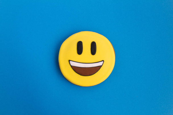 Smiley in the form of gingerbread on the blue background.Top view.Closeup.Copy space. - Fotografie, Obrázek
