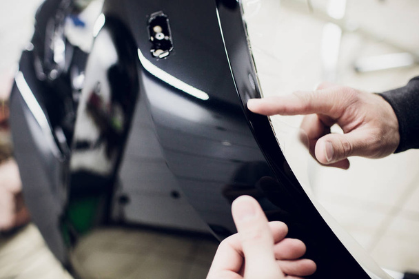 Worker hands installs car paint protection film wrap bumper - Фото, изображение