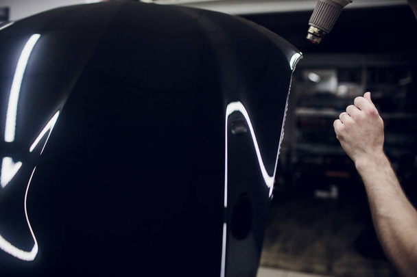 Worker hands installs car paint protection film wrap hood - 写真・画像