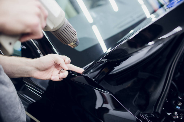 Worker hands installs car paint protection film wrap hood - Zdjęcie, obraz
