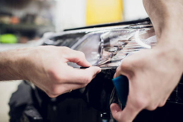 Worker hands installs car paint protection film wrap auto headlight - Fotó, kép