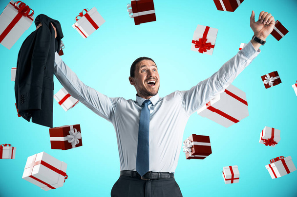Attractive businessman celebrating a lot of presents on blue background. Christmas and joy concept  - 写真・画像