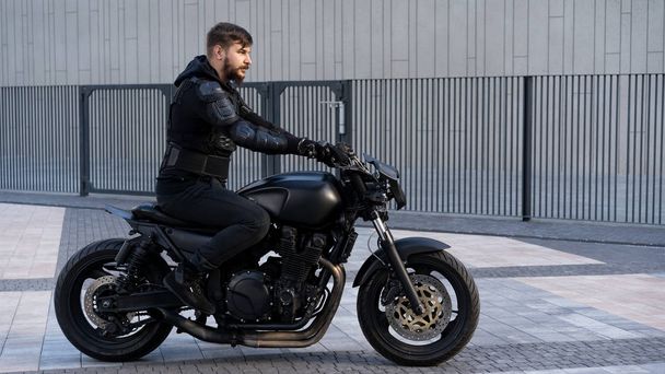 Man op een motorfiets zwarte motorfiets op de weg blijven - Foto, afbeelding