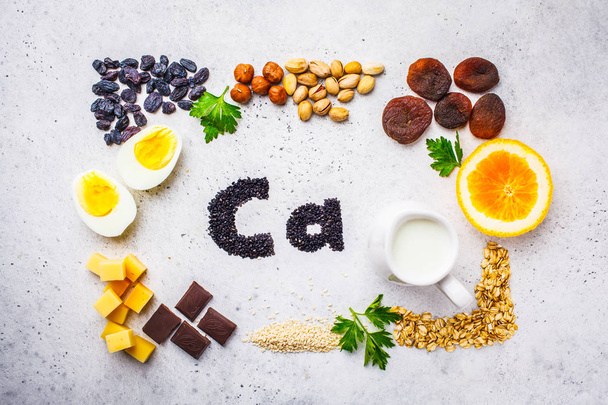 カルシウムの健康的な製品のソース。トップ ビュー、食品背景、Ca 成分: 穀物、ドライ フルーツ、乳製品、オレンジ、ナッツ、緑と白の背景にチーズ. - 写真・画像