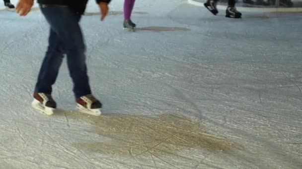 Az emberek korcsolyázni a jégpálya téli város esti. Láb a korcsolyázók a jégen, a Műjégpálya, első alsó test nézet sovány. Krikettezik családok, gyermekek, felnőttek és fiatalok éjszakai utcai piacon. A hagyományos vásár utca zsúfolt jég - Felvétel, videó
