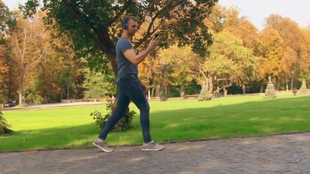 Guy chůzi na ulici pomocí mobilní boční pohled - Záběry, video