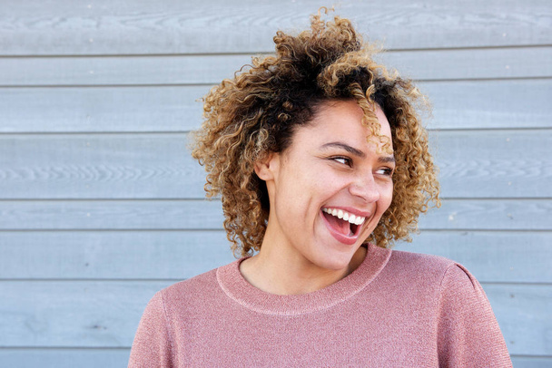 Nahaufnahme horizontales Porträt schöne afrikanisch-amerikanische Frau lacht gegen graue Wand - Foto, Bild