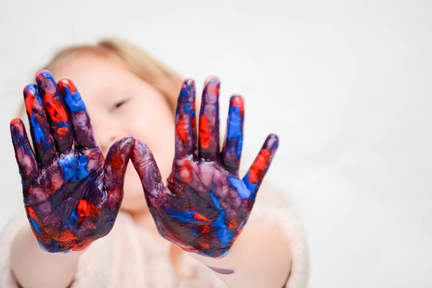 Ευτυχισμένο παιδί που παίζει με το χρώμα, το κορίτσι έχει χρώμα στα χέρια και τα δάχτυλα - Φωτογραφία, εικόνα