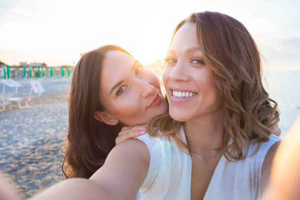 Two girlfriends making a selfie on the beach - Foto, afbeelding