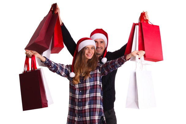 Happy beautiful couple holding many bags with christmas gifts isolated on white background - Фото, зображення