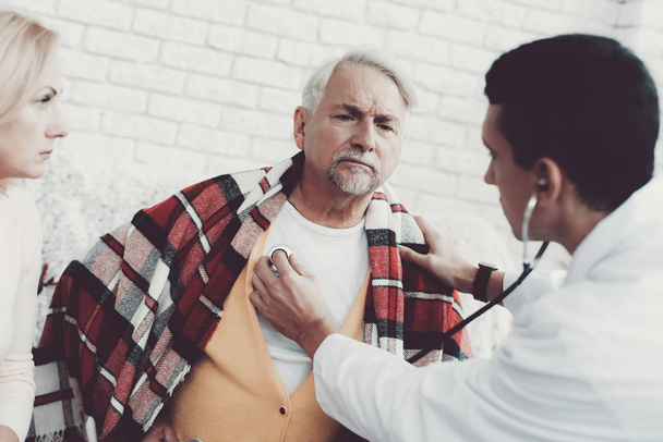 Young Doctor in Coat Visiting Old Couple at Home. Medical Healthcare Concept. Man in White Coat. Sitting on Sofa. Old Man with Blanket. Grandfather and Grandmother. People with Gray Hair. - Fotó, kép