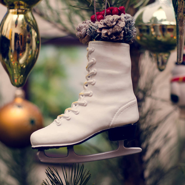 Skates toy as a Christmas and New Year decor on a spruce branch. - Zdjęcie, obraz