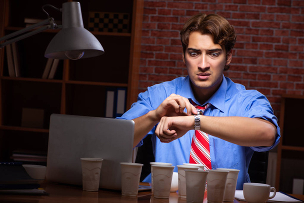 Young employee drinking coffee working at night shift  - Photo, Image
