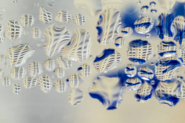 Makrofoto. abstraktes Aqua-Muster als Hintergrund. verdrehte Spiegelungen in Wassertröpfchen. Blaue Linien und mehrstöckiges Gebäude. - Foto, Bild