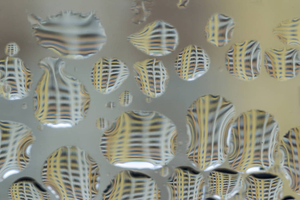 Macro foto. Abstract aqua patroon als achtergrond. Gedraaide reflecties van een meerdere verdiepingen tellend gebouw in druppels water. - Foto, afbeelding