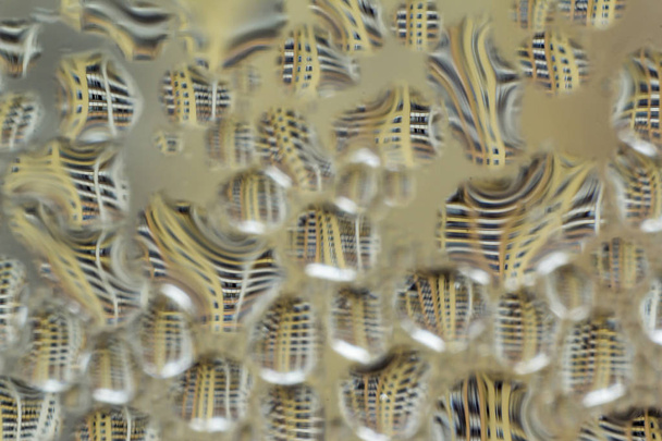 Makrofoto. abstraktes Aqua-Muster als Hintergrund. Verdrehte Spiegelungen eines mehrstöckigen Gebäudes in Wassertropfen. - Foto, Bild