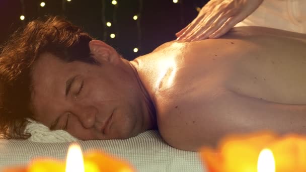 Feliz hombre sonriente teniendo placer durante el masaje en el hotel relajante
 - Imágenes, Vídeo