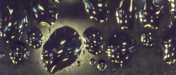 Foto macro. Patrón aqua abstracto como fondo. Reflejos retorcidos de colores de luces y faroles en gotas de agua
. - Foto, imagen