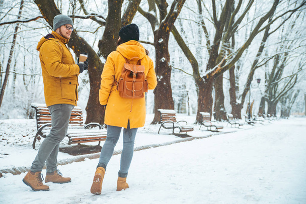 φίλοι περπάτημα από χιονίσει πάρκο με καφέ για να πάει. ζεσταθεί στην κρύα ημέρα. Χειμερινό πάρκο της πόλης. χώρο αντίγραφο - Φωτογραφία, εικόνα
