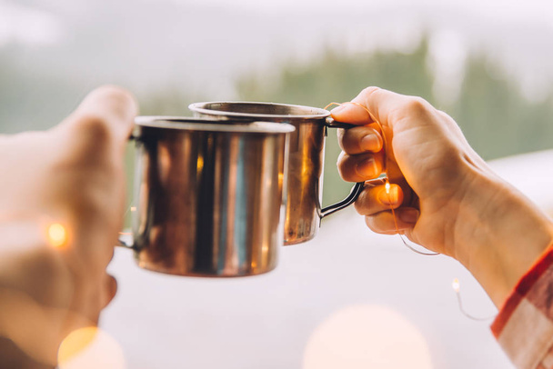 couple hands holding two metal cups with warm up tea hiking concept - Foto, Bild