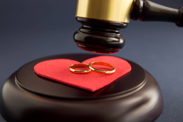 Обручальные кольца на фигуре разбитого сердца с дерева, молоток судьи на деревянном фоне. Процесс развода
 - Фото, изображение