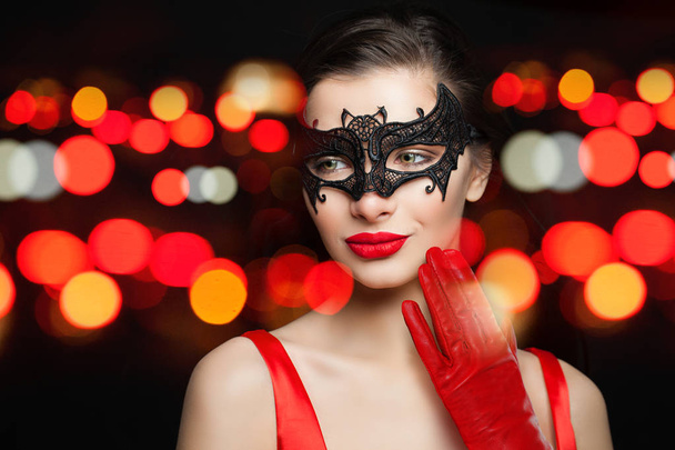 Glamorous kobieta z czerwonymi ustami makijaż i czarny Karnawał Maska na noc tło bokeh. Makijaż i kosmetyki koncepcja - Zdjęcie, obraz