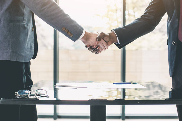 Two confident business men, African American and Caucasian shaking hands during a meeting in the office, success, dealing, greeting and partner concept. - Photo, Image