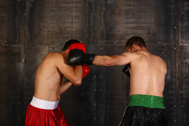 Portrait latéral rapproché de deux boxeurs hommes en gants de boxe pendant l'action de combat, vue en angle bas - Photo, image