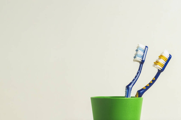 Due spazzolini da denti usati in un bicchiere di plastica su sfondo bianco. Il concetto di cambiare spazzolini da denti, igiene orale, odontoiatria, famiglia amichevole
 - Foto, immagini