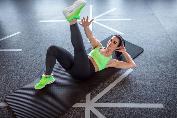 Woman performing exercise on gym floor - Foto, afbeelding