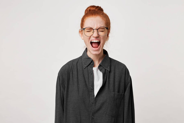 Close up of scared red-haired girl, feels frightened afraid, mouth wide opened as screaming shouting yelling loud, eyes closed, over white background - Foto, Imagen