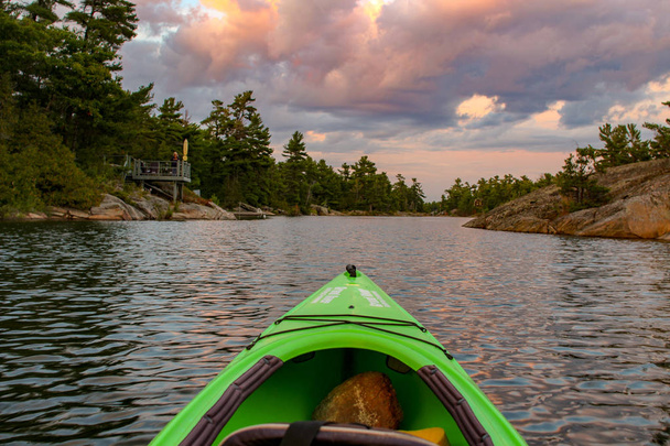 Faire du kayak sur une eau calme et paisible vers le coucher du soleil. Tourné du point de vue du pagayeur
. - Photo, image